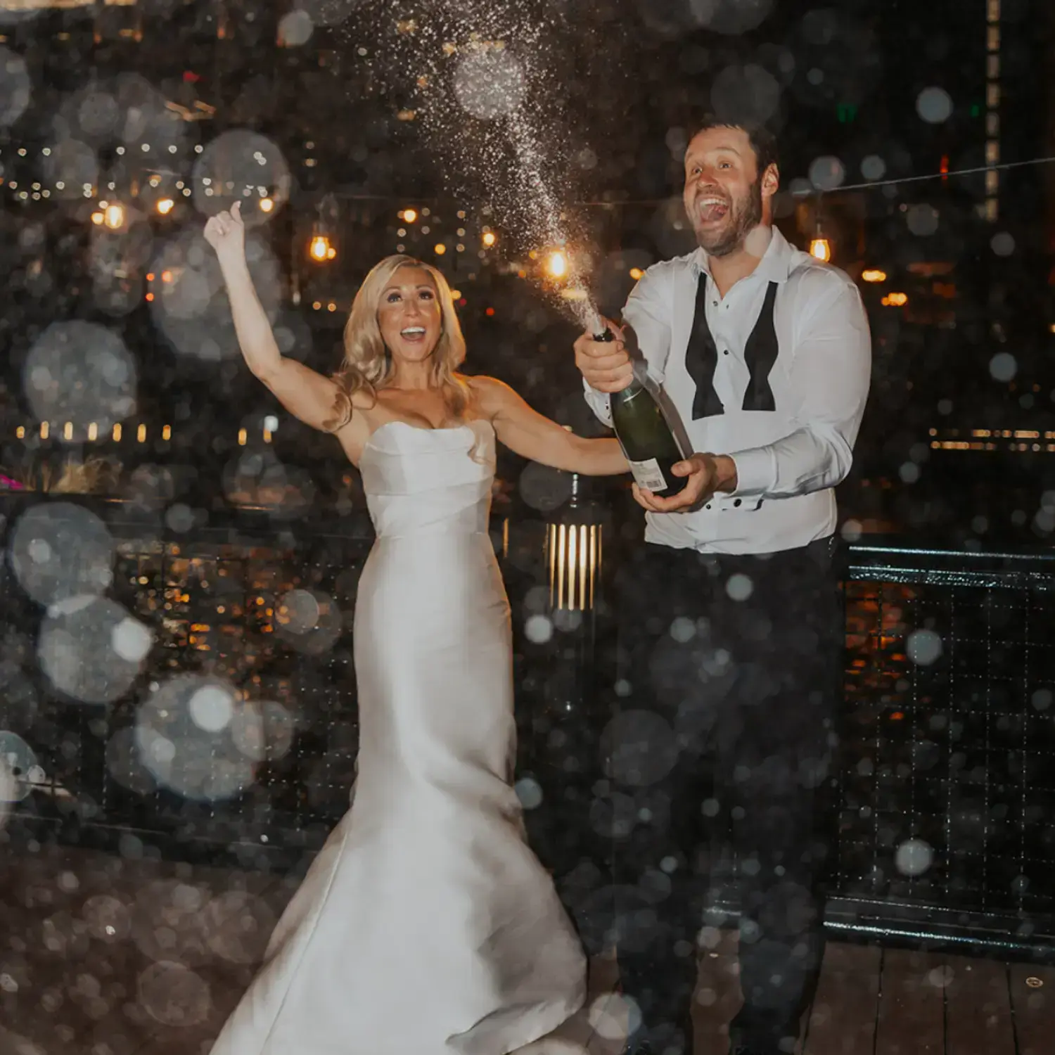 A newly married couple opening a bottle of champagne